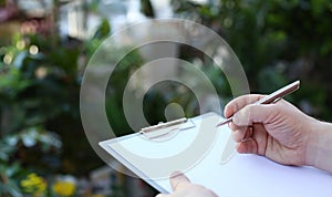 Human Hand Writing on Clipboard with White Paper