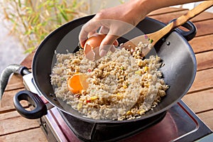 Human hands adding egg into fried rice