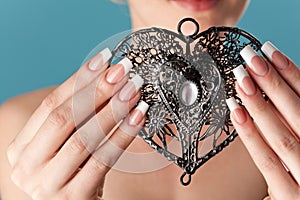 Human hands with beautiful manicure hold a openwork heart