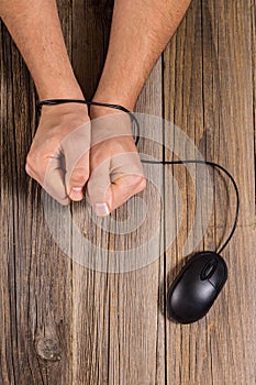 human hands bound by wire computer mouse as a concept the dependence of man on modern technology, Internet