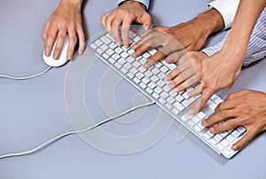 Human hands on computer keyboard with one hand using computer mouse