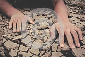 Human hands on cracked dry ground