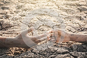 Human hands helping on cracked dry ground