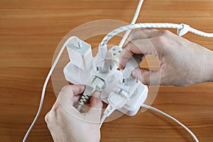 Human hands hold plug, Multiple plugs on table electrical outlet is dangerous overload