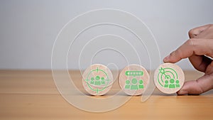 Human hands hold target customer icons on circle wooden planks. Placed on a wooden background, it represents selected business