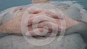 Human hands hold together on a man belly