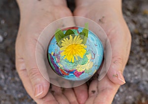 Human hands holding earth globe with dandelion flower and soil. Clean planet, green environment, ecology concept
