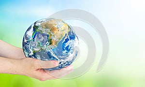 Human hands holding earth globe over blurred green and blue sky nature background. Elements of this image furnished by NASA