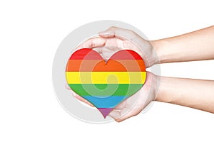 Human hands holding heart with rainbow flag as a symbol of LGBT
