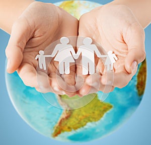 Human hands holding paper family over earth globe