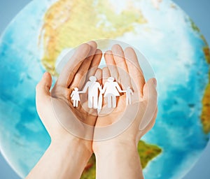 Human hands holding paper family over earth globe