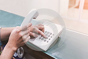 Human hands holding telephone handle and dialing