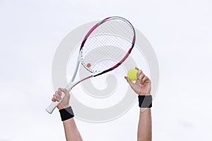 Human hands holding tennis ball and a racket on background of th