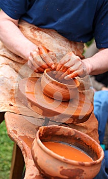 Human hands making clay pot on a potter's wheel