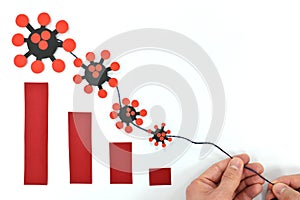 Human hands pulling downward a decreasing bar graph trend of coronavirus covid-19 pandemic cases.