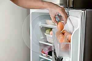 Human hands put chicken eggs in the egg-laying compartment in the refrigerator