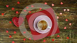 Human hands put cup of coffee on red napkin and set fire heart-shaped candle.