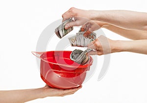 Human hands putting dollars in a red hard hat