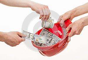 Human hands putting dollars in a red hard hat