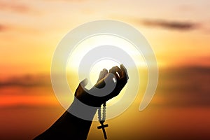 Human hands with rosary beads raised while praying to god