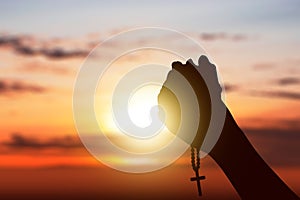 Human hands with rosary beads raised while praying to god