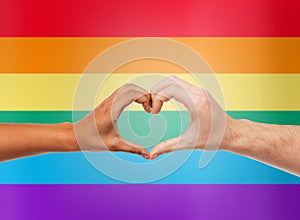 Human hands showing heart shape over rainbow