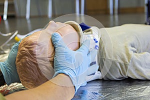 Human hands stabilisations the neck from a medical training puppet