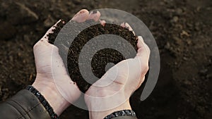 Human hands take a sample of the black fertile soil