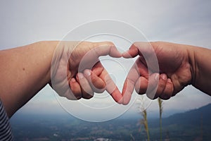 Human hands together in heart shape selectable focus sky background love day concept.