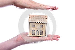 Human hands with toy wooden house isolated on white