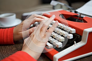 human hands writing on red typewriter