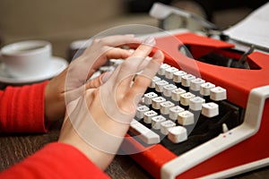 human hands writing on red typewriter