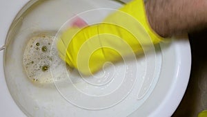 Human hands in yellow rubber gloves are washing with brush and toilet detergent, toilet in loo. Work on hygiene at home