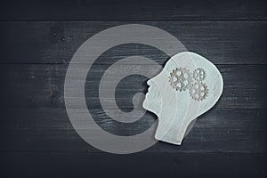 Human head and face with gear sign  on wood table background. Brain of thinking about driving the organization , Symbol of Process