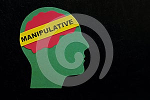 Human head profile with word manipulative in dark black background. Manipulative behavior concept. photo