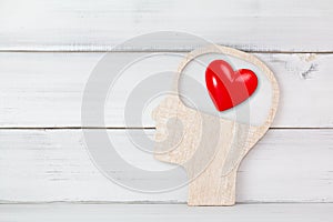 Human Head and Red Heart inside brain shape over white wood background. Symbol for falling or being in love, liking, emotions and