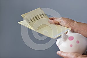 Human holding saving account passbook and piggy bank in hands