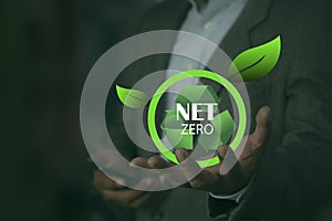 Human holds a green recycling symbol with the words net zero. CO2 level gauge percentage reduced to 0 Net Zero. Greenhouse gas