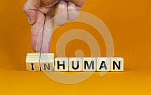 Human or inhuman symbol. Businessman turns wooden cubes and changes the word inhuman to human. Beautiful orange table orange