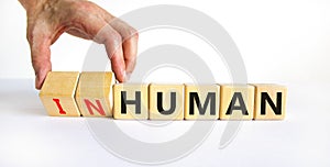 Human or inhuman symbol. Businessman turns wooden cubes and changes the word inhuman to human. Beautiful white table white