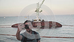 Human journalist make report on sunken tanker Delfi in Odessa. Male blogger shoots video on phone, publish post about
