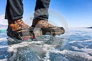 Human legs in hiking boot in ice crampons on the texture Baikal