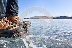 Human legs in hiking boot in ice crampons on the texture Baikal photo