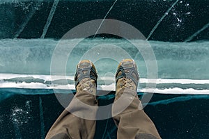 Human legs in hiking boot in ice crampons on the texture Baikal ice