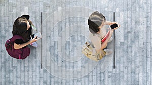 Human life in Social distance. Aerial top view with two student women with smartphone stand at grey pavement street road with