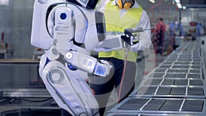 Human-like robot starts working with a drill after a corresponding command from a factory worker