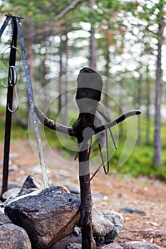 Human-like snag with glove at campfire.