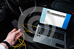 Human making car diagnostics using OBD device and computer.