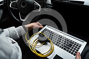 Human making car diagnostics using OBD device and computer.