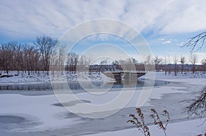 Human managed structure dam or bridge near a coal power plant - near the Minnesota River on a sunny, cold, snowy winter day